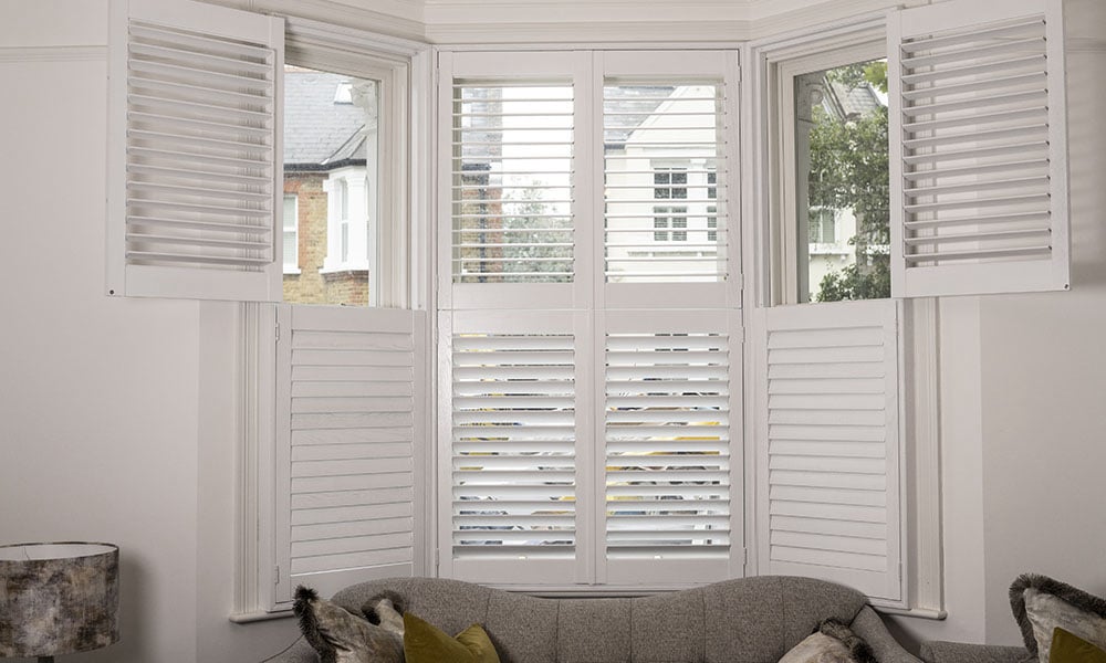 White tier-on-tier plantation shutters fitted to a bay window