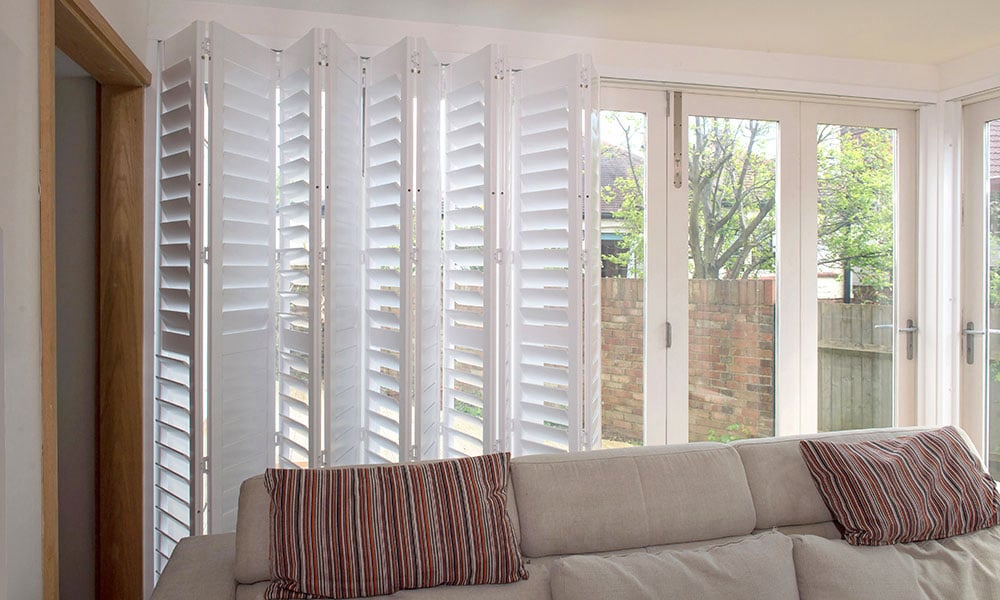 Tracked bi-fold shutters installed full height in a living room