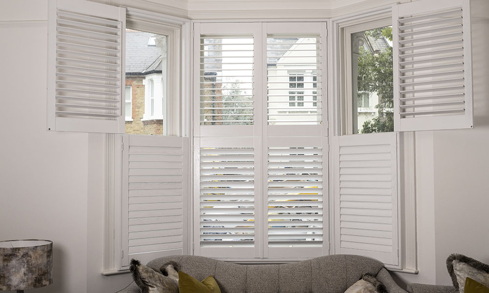 Bay window plantation shutters Hampshire bright living room — tier-on-tier fitted shutters